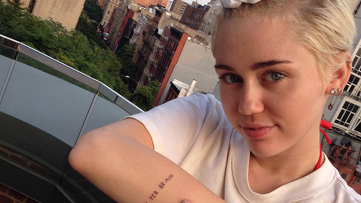 Miley visar sin tatuering som Keith har gjort. 